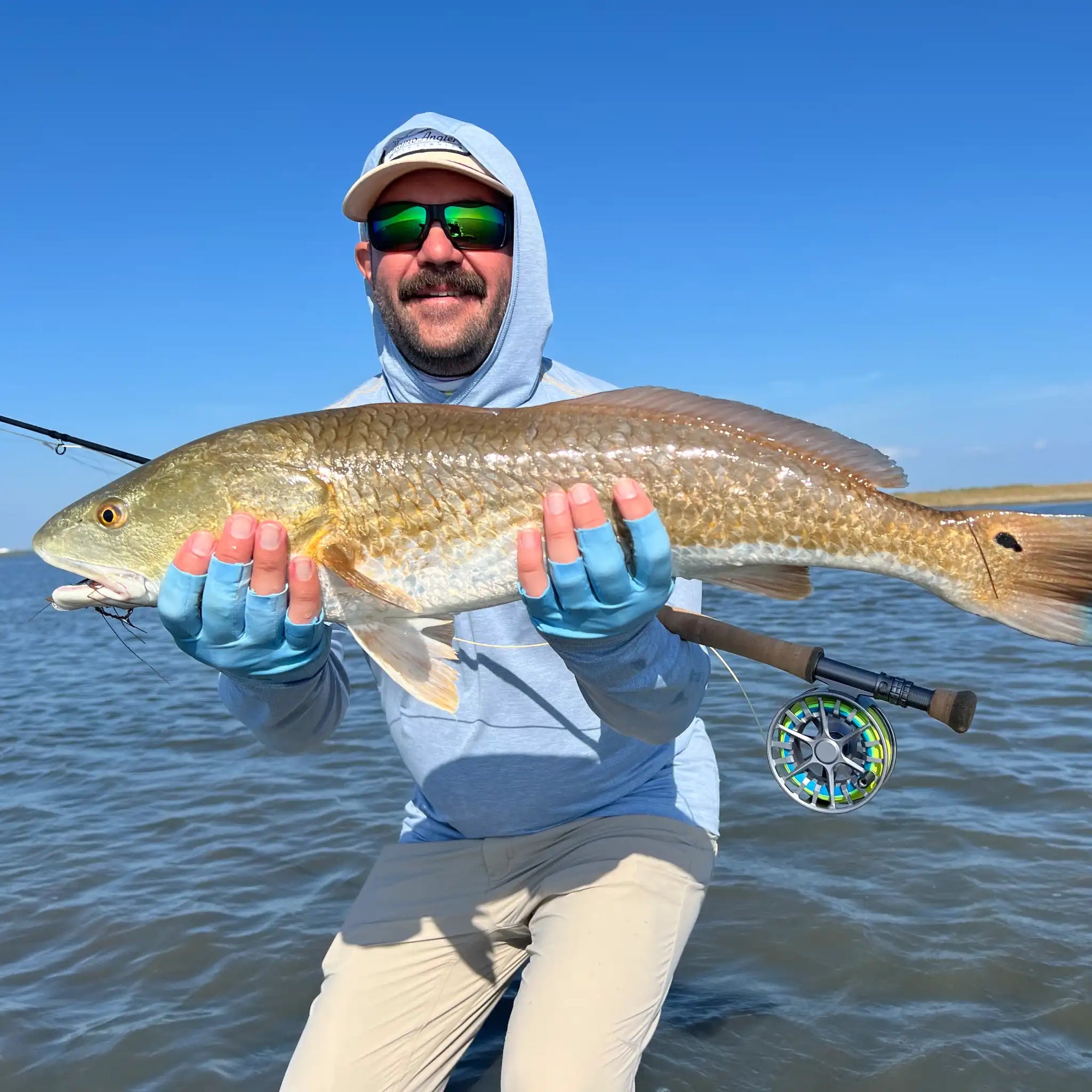 Man holding large redfish with a douglas sky fly fishing rod and a lamson guru reel